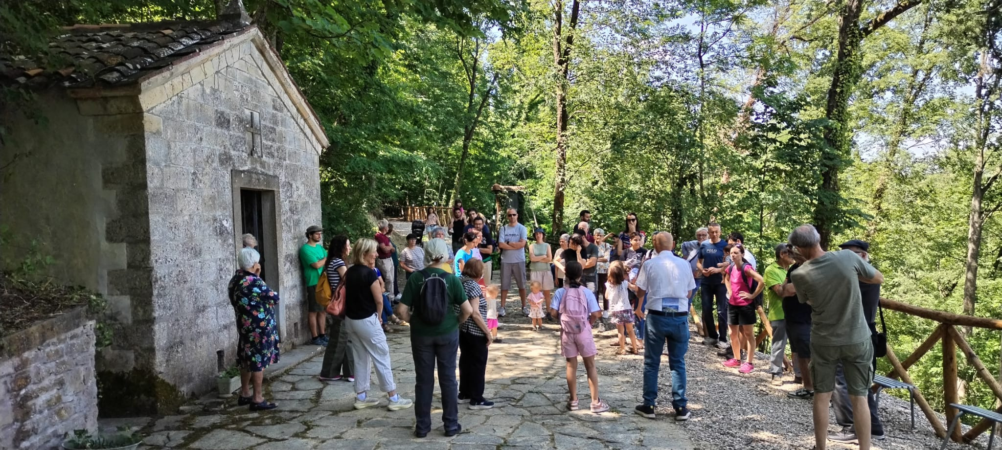 Famiglie riunite all'aperto davanti a una chiesetta, alla festa della famiglia